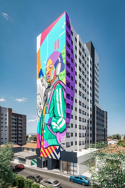 Fachada externa de edifício residencial com grande grafite colorido na lateral