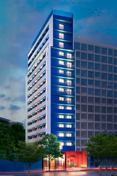 Fachada do edificio a noite com iluminacao azul destacando a torre principal.