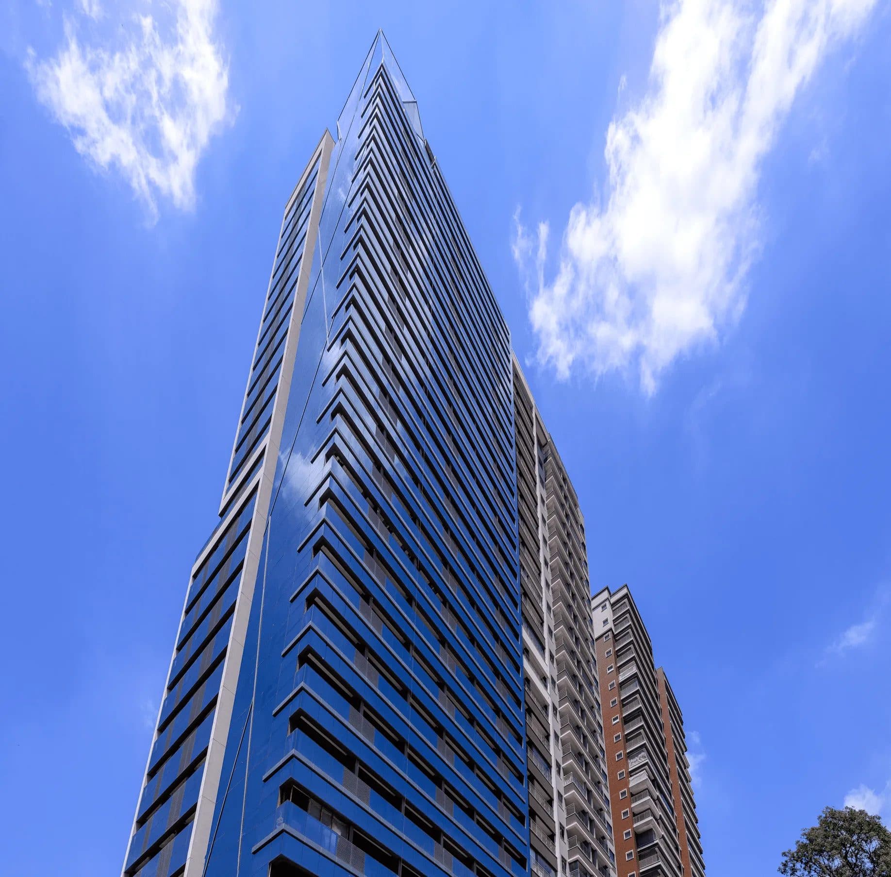 Fachada de edificio alto com fachada de vidro azul eceu azul ao fundo.