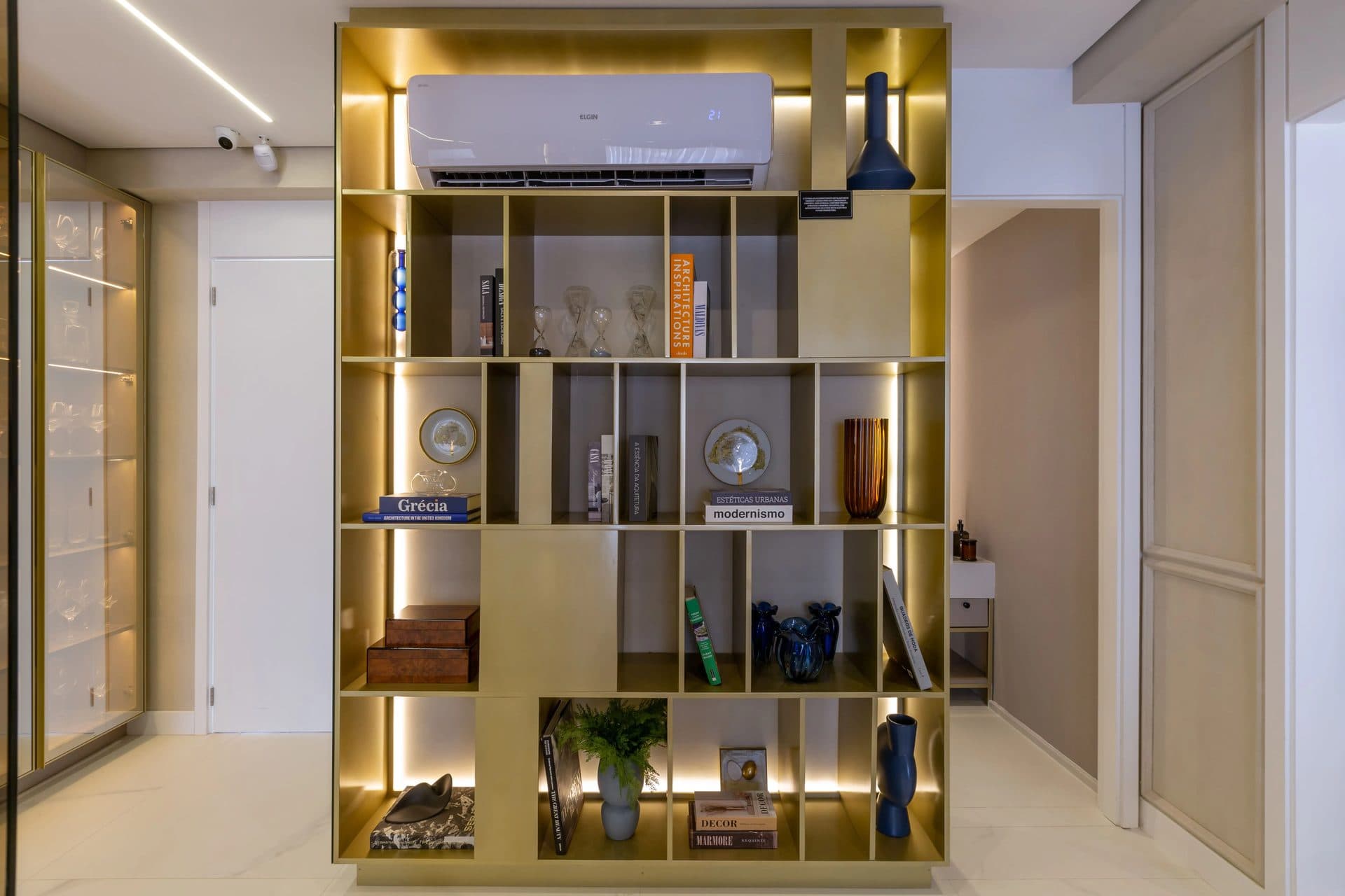 Estante aramada dourada com livros e objetos decorativos