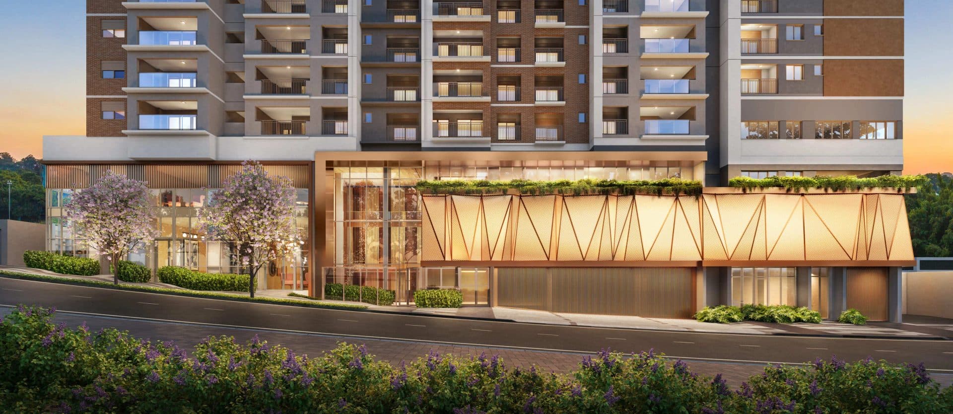 Fachada do edifício residencial com térreo comercial, portaria em vidro e paisagismo na calçada.