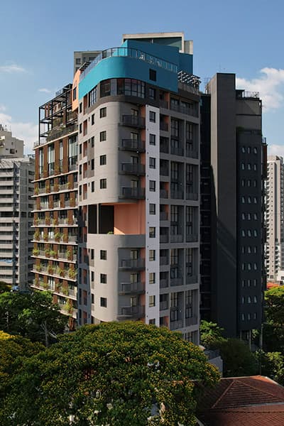 Vista externa da fachada lateral de um prédio residencial com varandas.