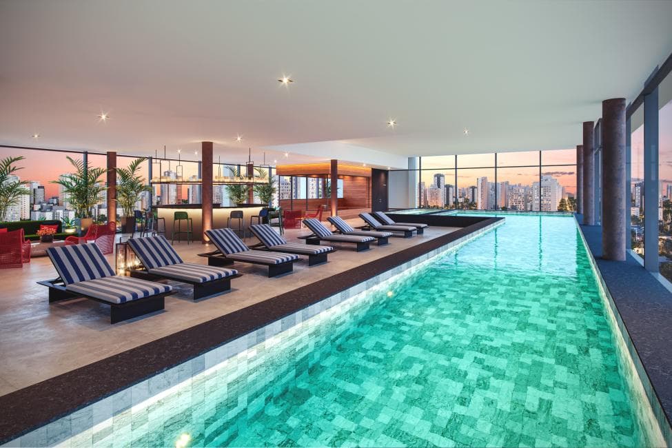 Piscina coberta com espreguiçadeiras e vista panorâmica para a cidade.