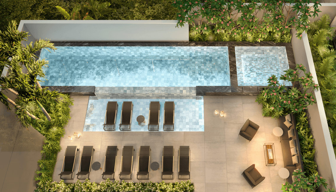 Área da piscina com espreguiçadeiras, deck molhado e paisagismo iluminado.